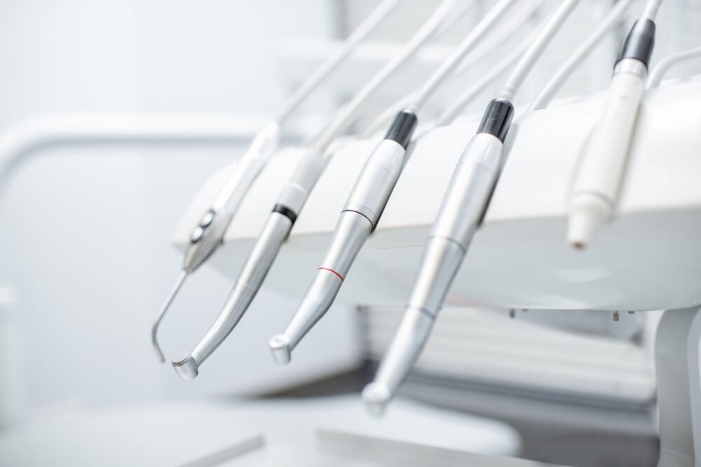 Odontologas atlieka dantų gydymą, naudodamas profesionalias įrangas, pacientui sėdint odontologinėje kėdėje